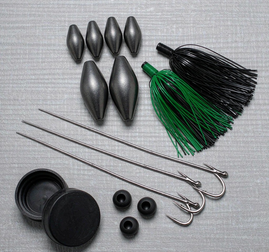 Flat lay of kit contents: tungsten weights, punch skirts, flipping hooks, bobber stoppers and storage tin